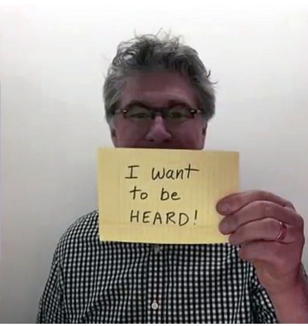 man holding paper with "I want to be heard" written