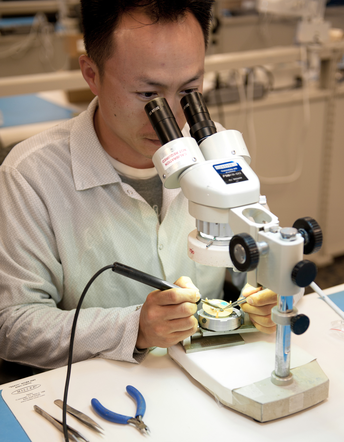 man working on hearing aid under microscope