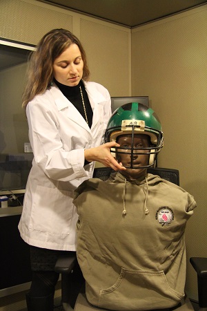 Annette Mazevski AuD PhD measures sound levels with a regulation football helmet using Kemar
