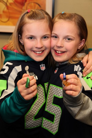 Erin and Riley Kovalcik proudly show off their Seattle Seahawks blue-and-green Oticon Sensei hearing instruments