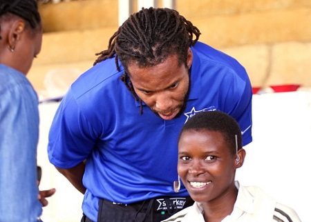 Larry Fitzgerald, Arizona Cardinals wide receiver, fits a patient with hearing aids at a Starkey Hearing Foundation mission