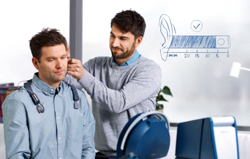 Doctor fitting patient with hearing aids