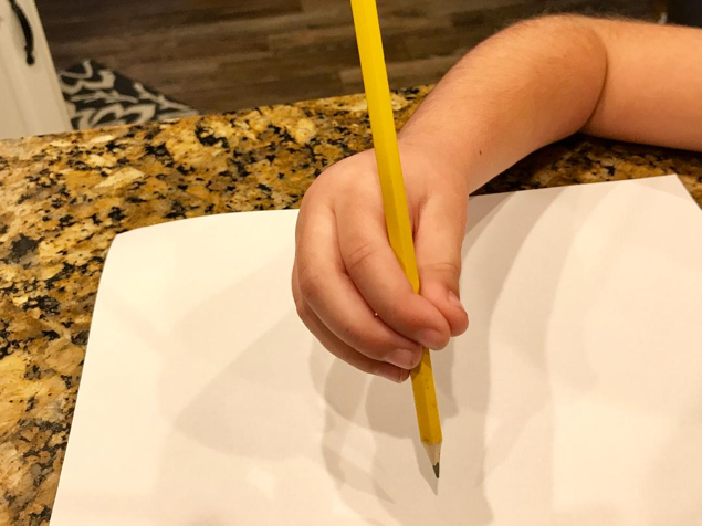 Quadrupod pencil grasp demonstrated by a child hand holding a pencil