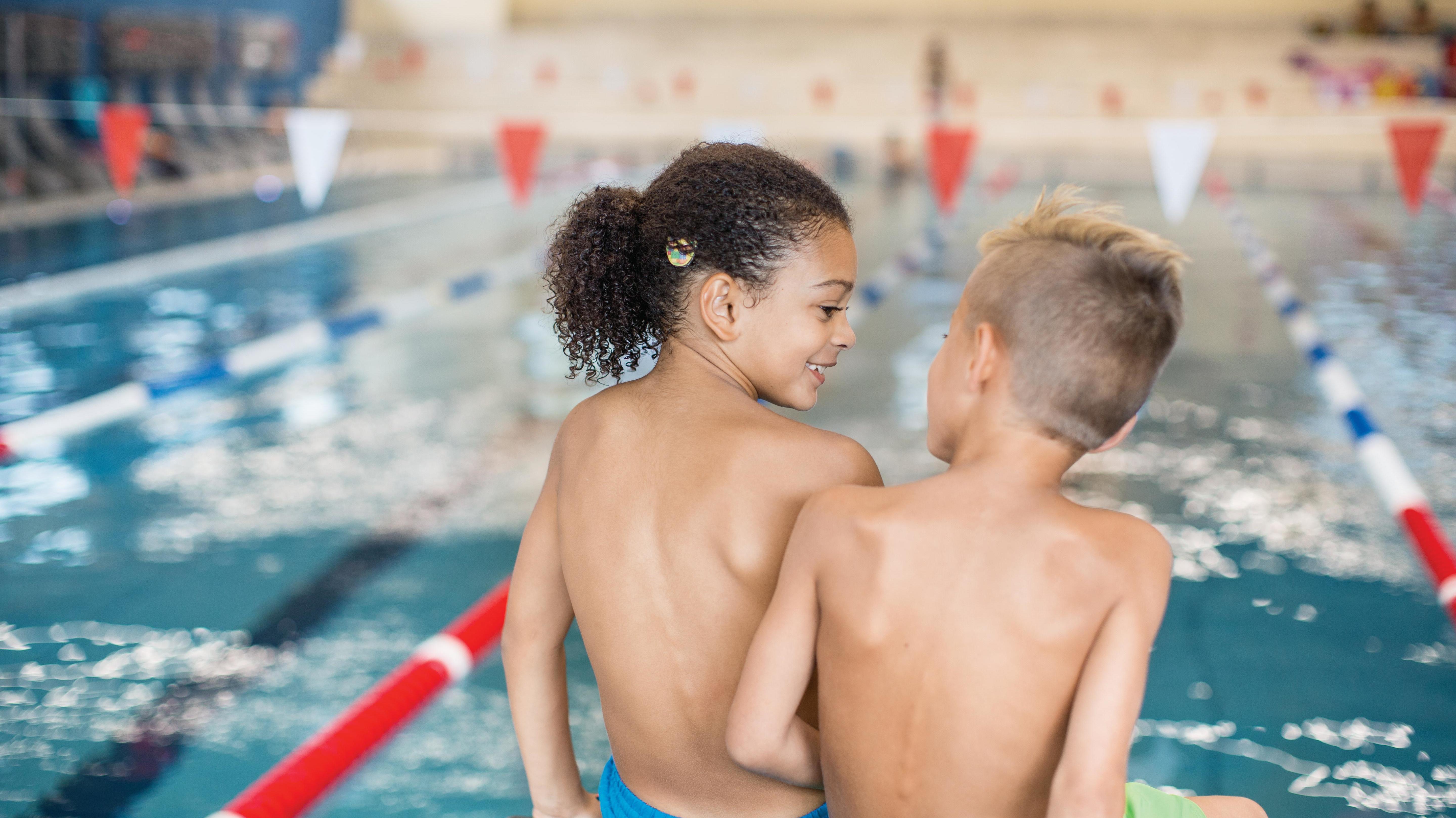 image of two children sitting by a pool wearing SAMBA