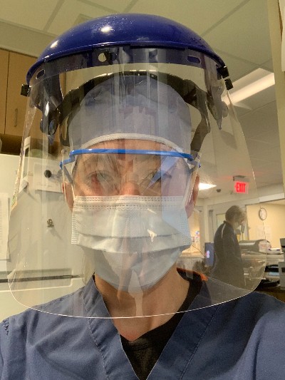 Female physician wearing scrubs, mask and face shield