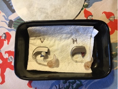 hearing aids sitting on a paper towel with letters V and H written on it