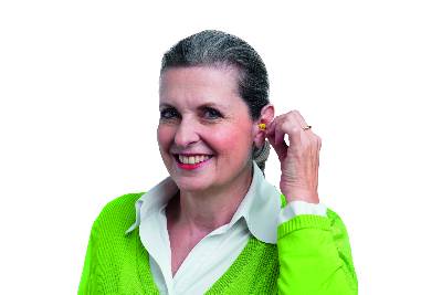 Smiling woman inserting small device into her left ear.