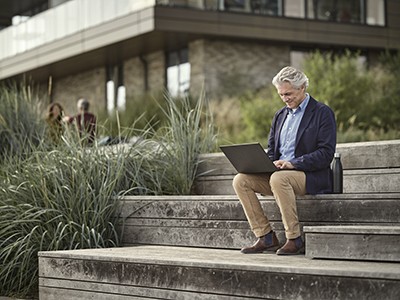 man sitting outside typing on laptop