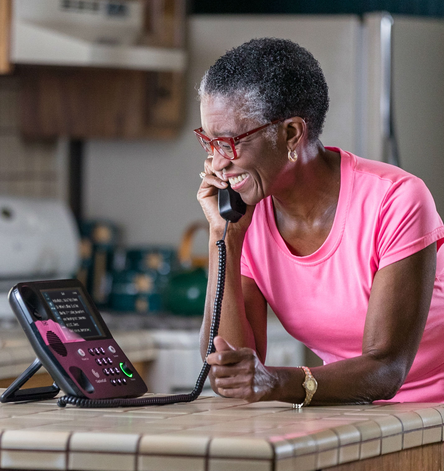 Smiling woman using a caption call telephone