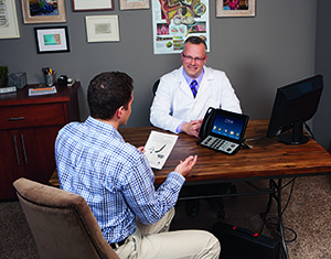 Audiologist at desk speaking with a male patient